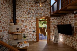 een woonkamer met een tv en een stenen muur bij Villa Kallia & George in Malia