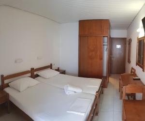 1 dormitorio con 2 camas blancas y armario de madera en Hotel Venus en Paralia Katerinis