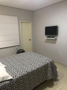 a bedroom with a bed and a flat screen tv at Suite Confortavel em Chapada dos Guimaraes in Chapada dos Guimarães