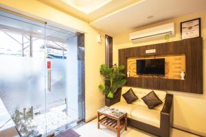 Hygienic Hotel Liberty Plaza في مومباي: غرفة معيشة مع أريكة وتلفزيون