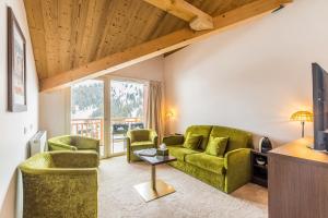 a living room with two green chairs and a tv at Madame Vacances Hôtel & Spa Le Mottaret in Méribel
