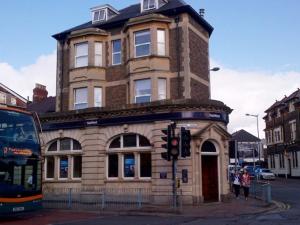 a building on the corner of a street with a bus at Richmond Road Guest House in Cardiff