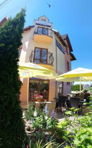 a building with a patio with tables and umbrellas at Villa Nobis in Łeba