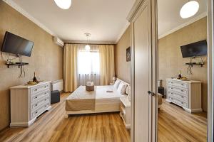 a bedroom with a bed and two dressers and a television at Hotel Fusion in Odesa