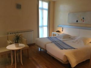 una habitación de hotel con una cama grande y una mesa en Hotel Nochendi en Cangas de Onís