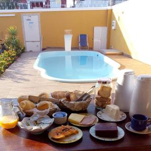 uma mesa com uma bandeja de comida ao lado de uma piscina em Pousada Marcos no Guarujá