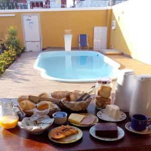 a table with a tray of food next to a swimming pool at Pousada Marcos in Guarujá