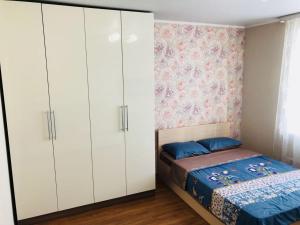 トムスクにあるАпартаменты на Савиных 4Аの白いキャビネットとベッド付きのベッドルーム1室