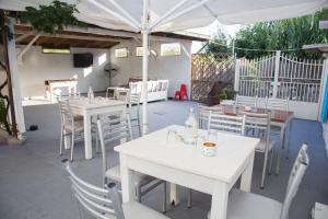 een patio met witte tafels en stoelen en een parasol bij Aristides Studios in Perama