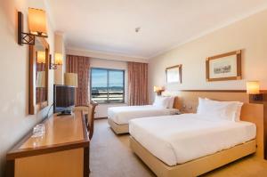 a hotel room with two beds and a television at Hotel Real Oeiras in Oeiras