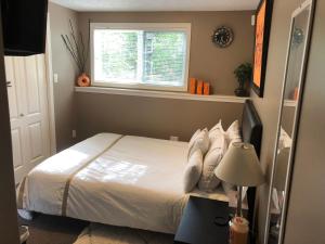a bedroom with a white bed with a window at Cozy and modern 3 bedroom in central location! in Victoria