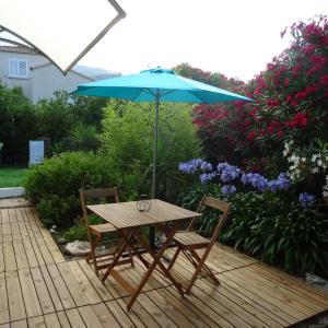 a wooden table and two chairs with an umbrella at 2 pièces indépendant avec son jardinet privé in Borgo