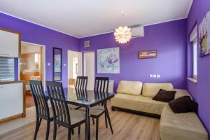 木洛希尼的住宿－KON-TIKI Apartments，一间拥有紫色墙壁和桌椅的用餐室