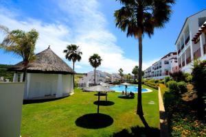 un patio del complejo con piscina y palmeras en Alcaidesa Golf, en Alcaidesa