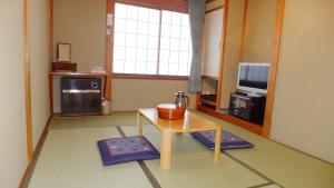 a living room with a table and a tv at Minshuku Iwatakan in Takayama