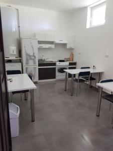 a kitchen with white tables and chairs in a room at Motel in Myszyniec