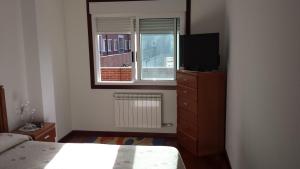 a bedroom with a bed and a tv and a window at Apartamento O pombal in Cambados