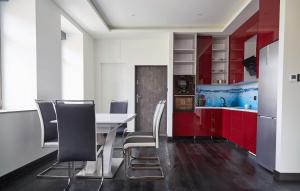a kitchen with red cabinets and a white table and chairs at Blue Door Apartment Ground Floor in Augustów