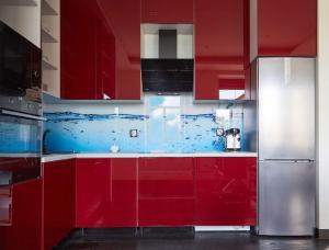 a red kitchen with red cabinets and a refrigerator at Blue Door Apartment Ground Floor in Augustów +13 photos
