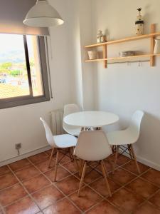 una mesa y sillas blancas en una habitación con ventana en Beach Castelldefels en Castelldefels