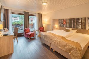 a hotel room with a bed and a desk and chairs at Best Western Plus Schwarzwald Residenz in Triberg