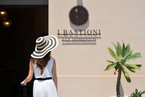 a woman wearing a hat walking past a wall with a clock at I Bastioni San Domenico - Boutique Hotel in Gallipoli