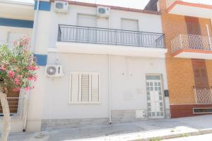 a white building with a balcony and a door at Casa vacanza “Grigio Perla” in Pachino