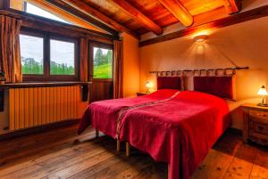 a bedroom with a red bed and a window at Agriturismo il Fiocco in Cesana Torinese