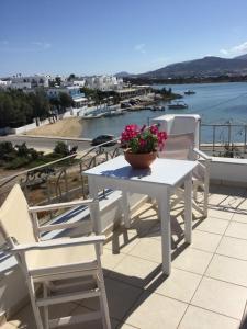 a white table and chairs with a flower pot on a balcony at Aegeo Inn Apartments in Antiparos Town