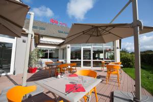 a patio area with tables, chairs and umbrellas at ibis budget Cherbourg - La Glacerie in Cherbourg en Cotentin