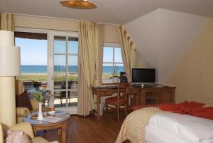 a bedroom with a bed and a desk with a computer at Romantik Hotel Namenlos in Ahrenshoop
