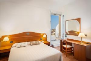 a bedroom with a bed and a desk and a window at Hotel Delfino in Caorle