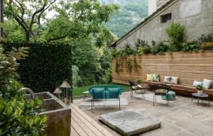 eine Terrasse mit einer Bank und Stühlen im Hof in der Unterkunft Palazzo Giani in Chiavenna