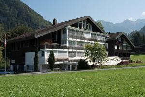 um grande edifício com um campo verde em frente em Hotel Klausenhof Flüeli em Flüeli