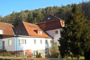 un bâtiment blanc avec un toit brun dans l'établissement Hotel Badstube, à Otterberg