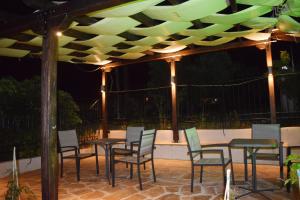 a group of chairs and tables under a pergola at Villa Madeleine Tower View in Nea Fokea