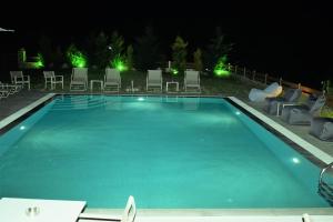 a swimming pool at night with chairs and lights at Villa Madeleine Tower View in Nea Fokea