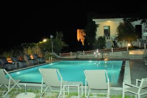 a swimming pool at night with chairs and a couch at Villa Madeleine Tower View in Nea Fokea