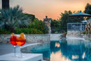 a wine glass sitting on a table next to a swimming pool at Masseria Valente in Ostuni