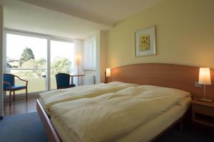 ein Schlafzimmer mit einem großen Bett und einem großen Fenster in der Unterkunft Hotel Klausenhof Flüeli in Flüeli