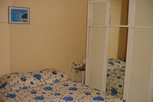 Schlafzimmer mit einem Bett mit einer blauen und weißen Bettdecke in der Unterkunft Hotel-appart Les Manguiers in Saint-Denis