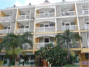 a large white building with palm trees in front of it at Hotel Les Manguiers Jardin de l'Etat Centre Ville Parking Gratuit Canal Sat in Saint-Denis