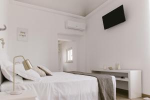 a white bedroom with a bed and a tv at Stazione a mare in Casalbordino