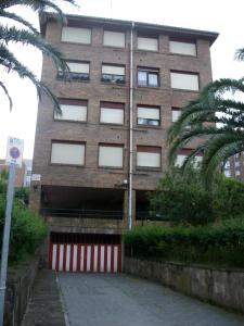 un edificio alto de ladrillo con garaje rojo y blanco en Apartamento Sobrevilla SDR IV, en Santander