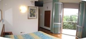 a bedroom with a bed and a door to a balcony at Hotel Boomerang - Check-in & Meals in front at hotel Sporting in Tabiano