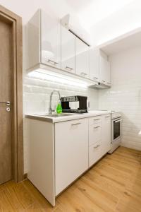 una cocina blanca con armarios blancos y fregadero en Raise cosy apartment, en Atenas