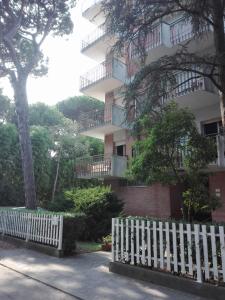a white picket fence in front of a building at Appartamento MiMa Pineta in Milano Marittima