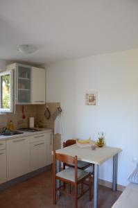 a kitchen with white cabinets and a table and chairs at Apartmani Gale in Okrug Donji