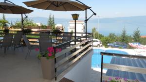 uma varanda com um guarda-sol e uma piscina em Villa Angelos em Ohrid