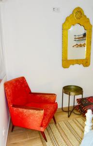 a red chair in a room with a mirror at Casinhas da Ajuda nº 29 in Lisbon